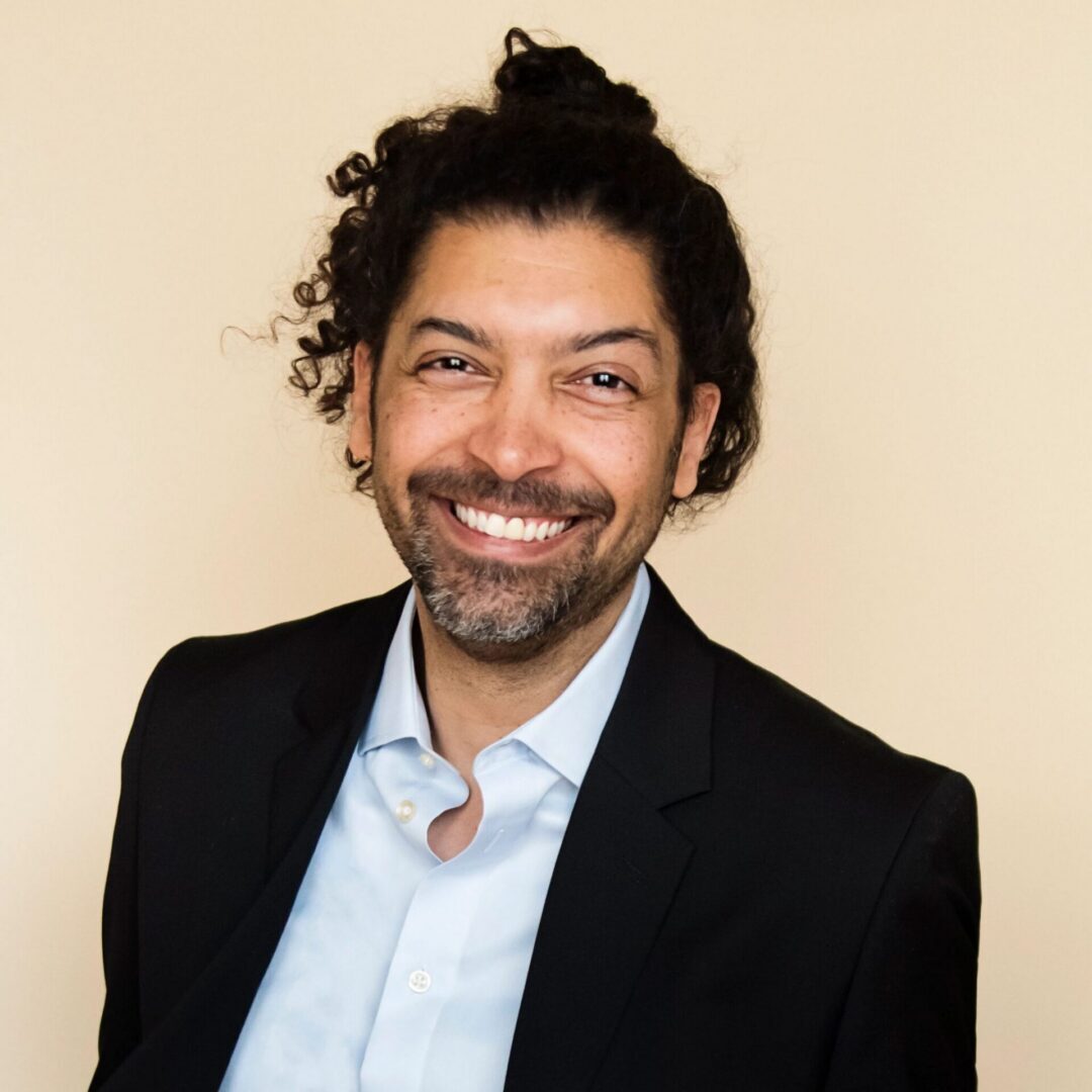 Smiling person in a suit and shirt.